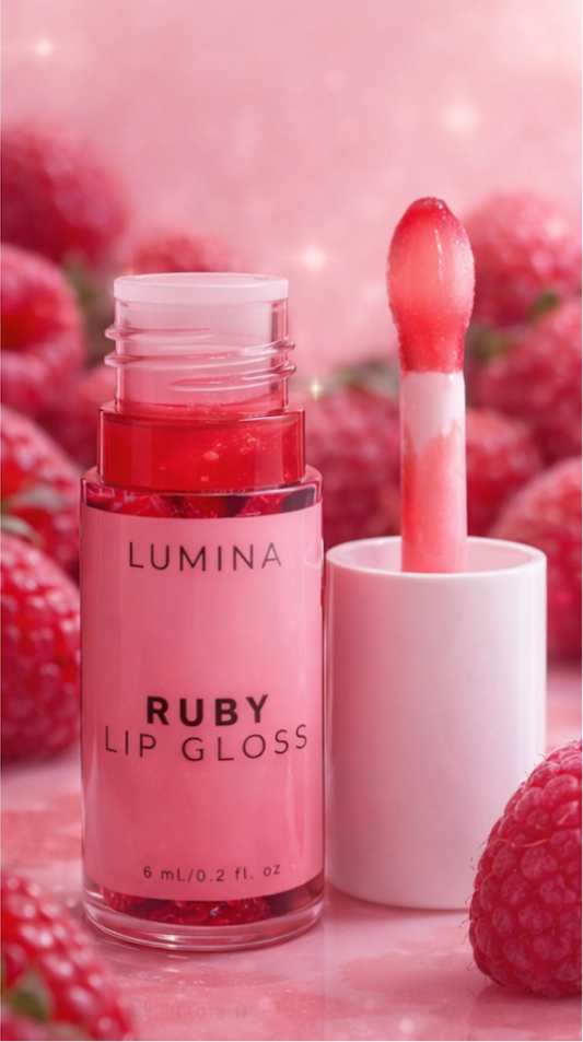 Lumina Ruby lip gloss with applicator on a pink background with raspberries